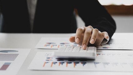 Businessman using a calculator to calculate numbers on a company's financial documents, he is analyzing historical financial data to plan how to grow the company. Financial concept.