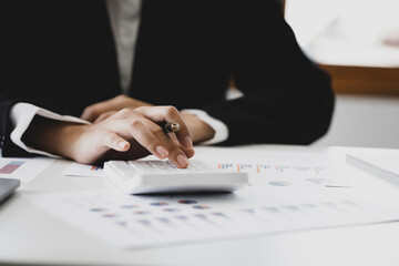 Businessman using a calculator to calculate numbers on a company's financial documents, he is analyzing historical financial data to plan how to grow the company. Financial concept.