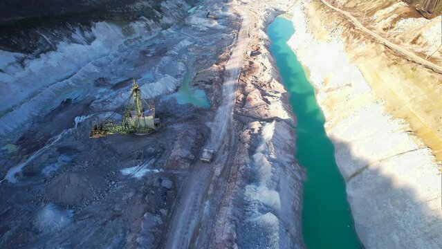 Mining dump truck transporting chalk rock from an open pit. Mining clay in limestone quarry. Anthropogenic landscape with mountains in open cast mine. 
