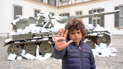 Europe, Italy, Milan April 2022  - Boy Child protest near a Military Tank submerged by white papers...