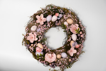 three blue spotted chicken eggs and a wreath of willow twigs on a white background, top view