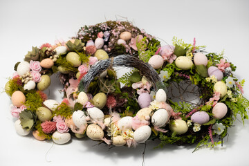 three blue spotted chicken eggs and a wreath of willow twigs on a white background, top view