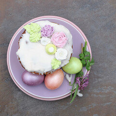 Easter cake with floral decor and colorful eggs on a plate, spring composition, top view, selective focus.