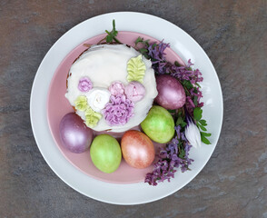 Easter cake with floral decor and colorful eggs on a plate, spring composition, top view, selective focus.