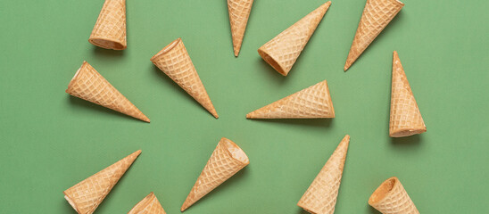 Empty waffle cones for ice cream on a green background. Top view, flat lay, banner.