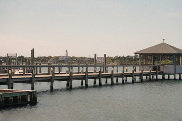 Obraz premium Landscape of Ocracoke Inlet, Lighthouse, Dock, Water and Buildings on Sunny Day