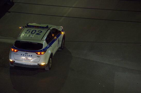 Elevated view of Greek police car with alarm lights on blocking the street during a night event in Thessaloniki, Greece.