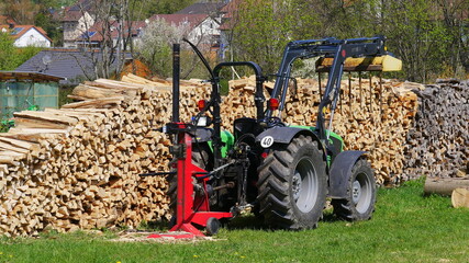 Traktor mit Holzspalter vor einem Holzstapel © turtles2