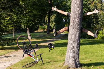 A cyclist bumps into a tree next to a path in a park.