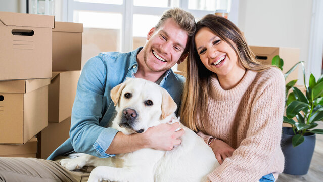 Husband and wife and their dog moving in new home - Young couple just moved into new apartment - People and relocation concept.
