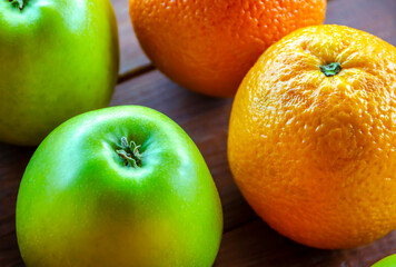 Green apple and orange close-up lying on a wooden table