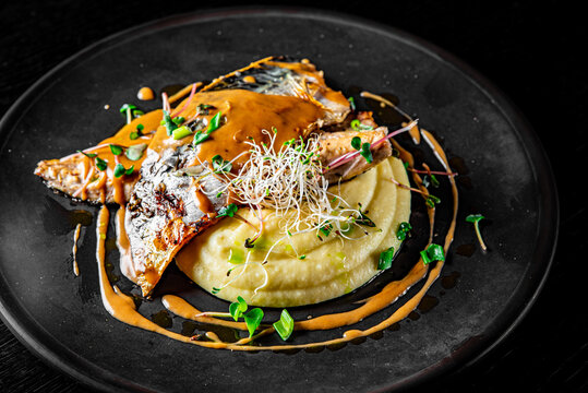 Fillet of mackerel with mashed potatoes and celery on dark background
