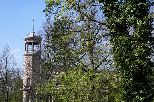 Schloss Biesdorf in Berlin im Fr&uuml;hling hinter B&auml;umen bei Sonnenschein