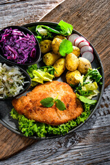Pork cutlet coated with breadcrumbs with potatoes and salads