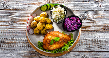 Pork cutlet coated with breadcrumbs with potatoes and salads