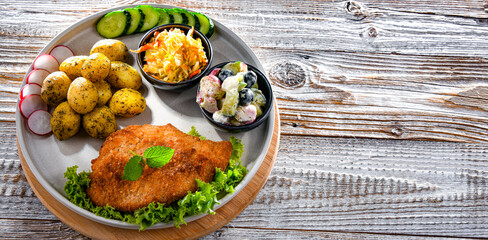 Pork cutlet coated with breadcrumbs with potatoes and salads