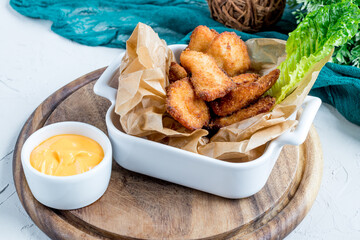 Fried chicken nuggets with cheese sauce on the board