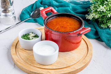 Borscht with sour cream on board on grey table