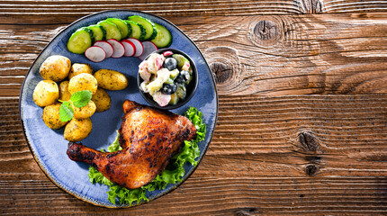 Baked chicken leg with potatoes and vegetable salads