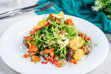 Salad with chicken liver and vegetables on white plate