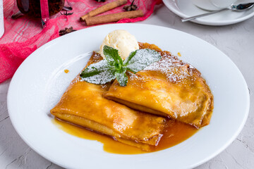 Pancakes with berries and honey and ice cream on a white plate