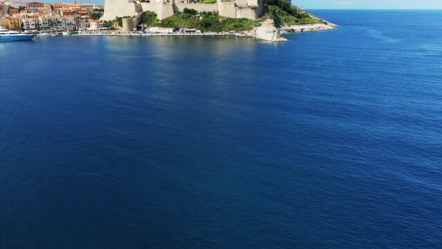 The city of Calvi and its medieval fort at the foot of the green mountains, in Europe, France, Corsica, by the Mediterranean Sea, in summer, on a sunny day.