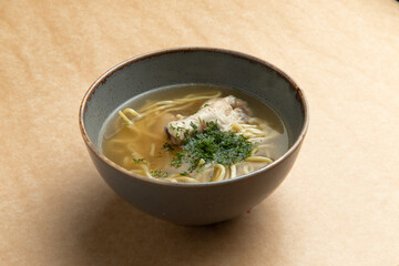 Traditional noodle soup with chicken. On a brown background.
