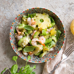 plate with salad with shrimps, pineapple and avocado on a light table
