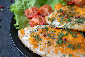 Fried fish on a plate with lettuce and cherry tomatoes, close-up. Healthy food, proteins, omega, fiber, vitamins.