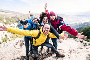 Group of hikers climbing mountains - Happy friends with hands up on the top of the mountain - Multiethnic people having trekking day out together