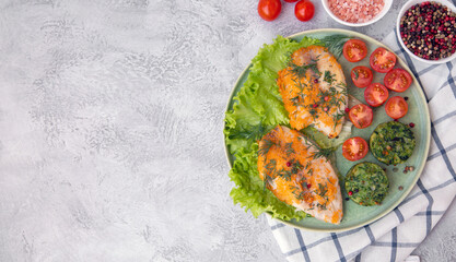Grilled fish on a plate garnished with green vegetable cutlets, top view with copy space. Healthy food, proteins, omega, fiber, vitamins.