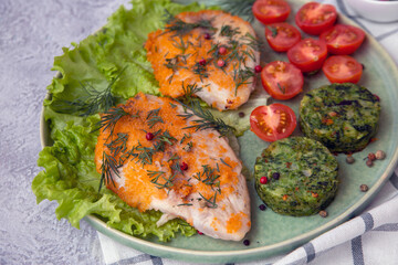 Fried fish on a plate garnished with green vegetable biscuits, close-up. Healthy food, proteins, omega, fiber, vitamins.