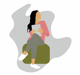 The girl is sitting on an ottoman with a tablet
