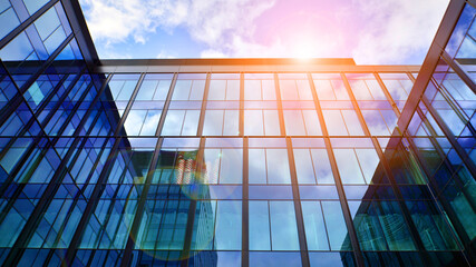 Glass buildings with cloudy blue sky background.  Perspective wide angle view to steel light blue background of glass.  Commercial modern city of future. Business concept of successful  architecture.