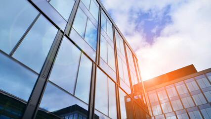 Obraz premium Glass buildings with cloudy blue sky background. Perspective wide angle view to steel light blue background of glass. Commercial modern city of future. Business concept of successful architecture.