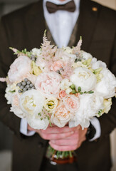 Obraz na płótnie Canvas Groom holding beautiful white wedding bouquet. Closeup