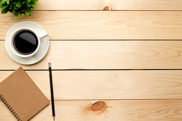 Top view office table desk. Workspace with blank, office supplies, pencil, green leaf, and coffee cup on wood background.