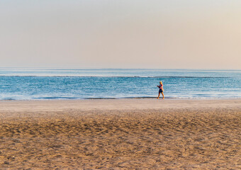 Shot of a woman walking on the empty beach. People