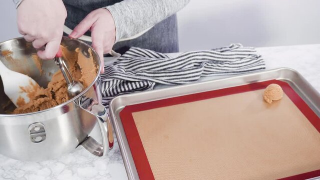 Time lapse. Step by step. Scooping peanut butter cookies dough with dough scooper into the baking sheet.