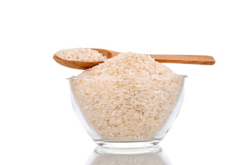 Uncooked organic rice with wooden spoon and glassware, macro, isolated on white background.