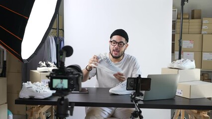 Young attractive Asian man blogger or vlogger looking at camera reviewing product and merchandise. Business online influencer on social media concept.