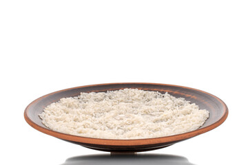 Uncooked organic rice on a clay plate, macro, isolated on a white background.