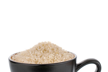 Uncooked organic rice in a ceramic black cup, macro, isolated on a white background.