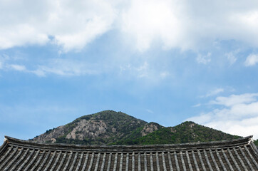 Fototapeta na wymiar Clouds over the mountains on a nice day. Korean traditional roof under it
