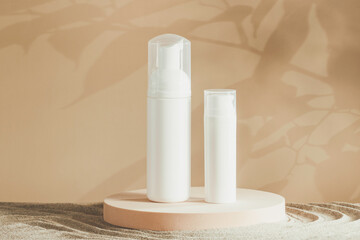Two white blank plastic packaging cosmetic pump bottles for mousse foam cream and lotion stand on...