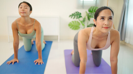 Obraz premium Attractive female coach teach people in the yoga class. People practicing lesson with instructor. Exercise and stretching healthy lifestyle at home. Meditating and relaxation concept. Indoor activity
