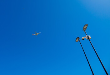 lamp post against sky with an airplane 