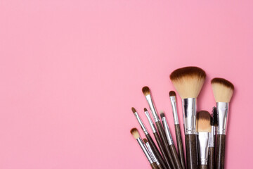 Cosmetic brushes, everyday makeup tools on pink background, closeup. Flatlay.