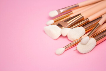 Cosmetic white brushes, everyday makeup tools on pink background, closeup. Flatlay.