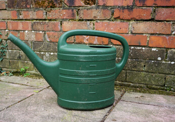 green watering can on patio surface. Plastic watering can for gardening use. 